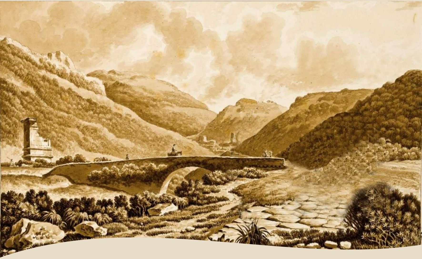 Ponte di pietra che attraversa una valle con montagne sullo sfondo e rovine antiche